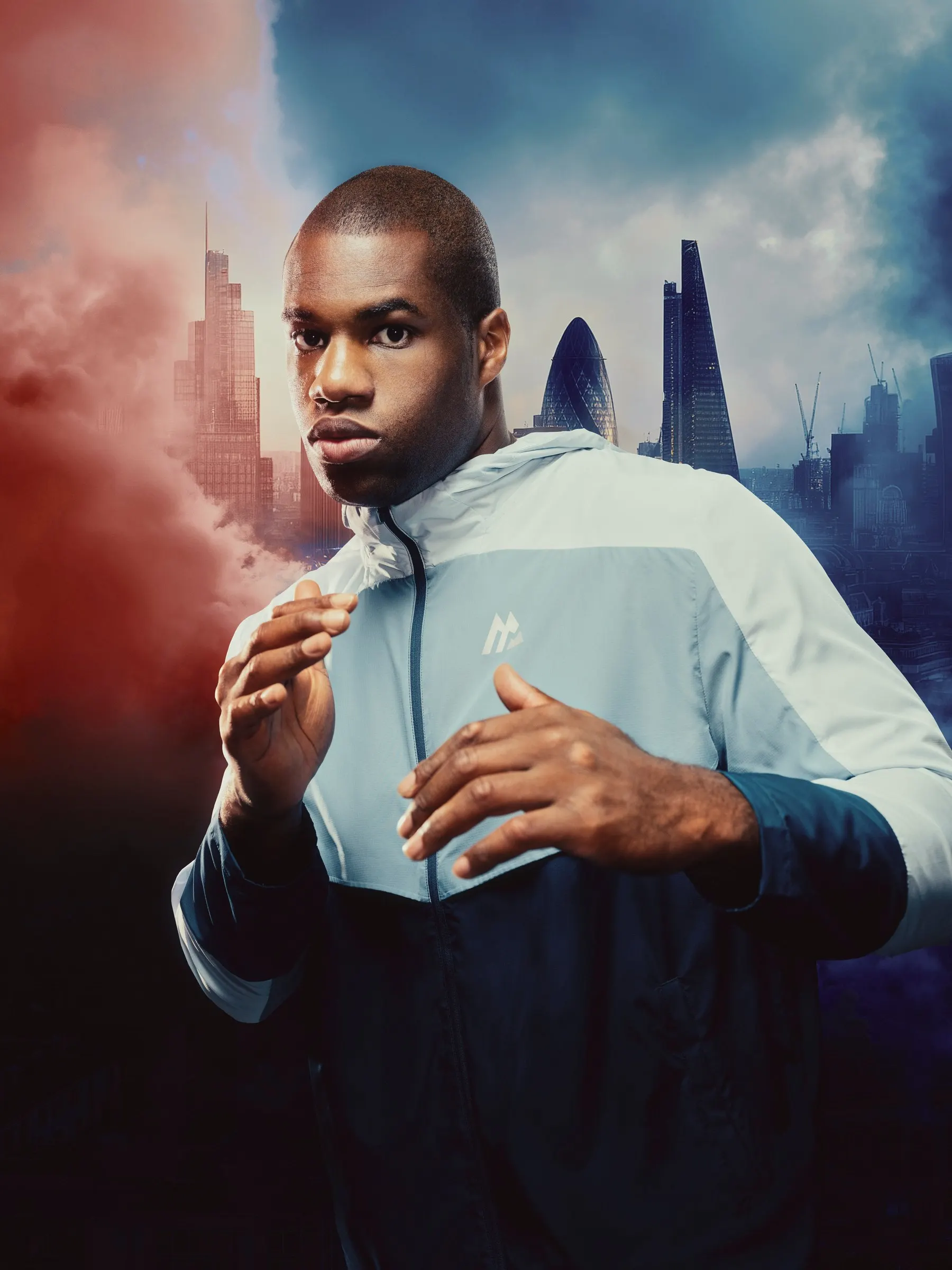 Daniel Dubois in a pale blue Montirex jacket, guard up, against a London skyline in red and blue smoke