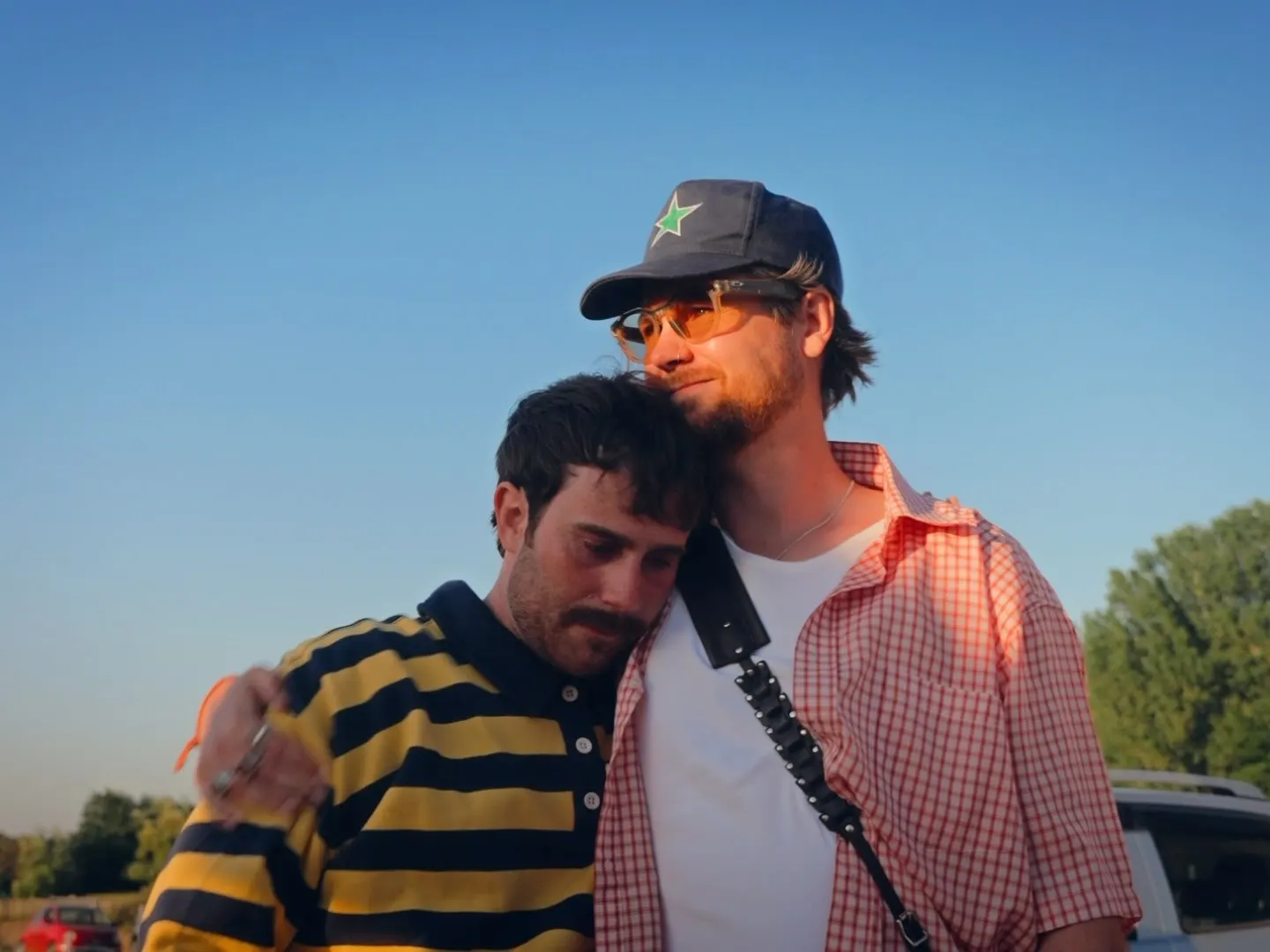 Will Beach and Sam Tompkins on the Heated Seats shoot: Sam, in a yellow and black striped top, leans his head on Will's shoulder at golden hour